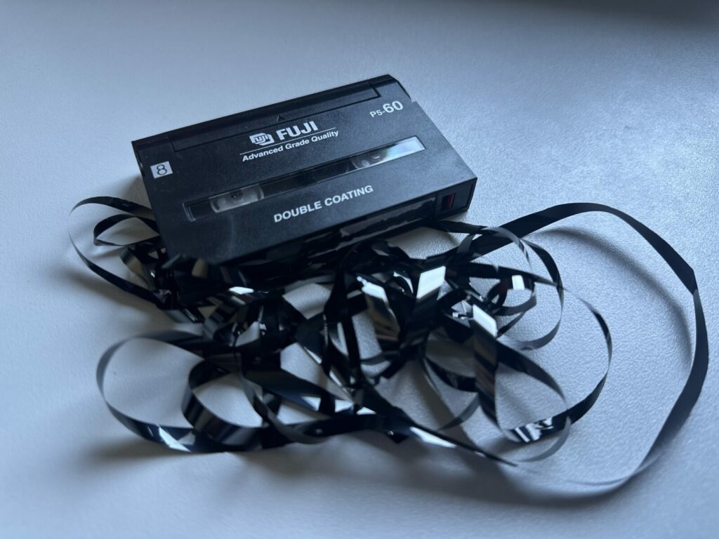 Cassette Video8 avec la bande magnétique déroulée et emmêlée avant réparation