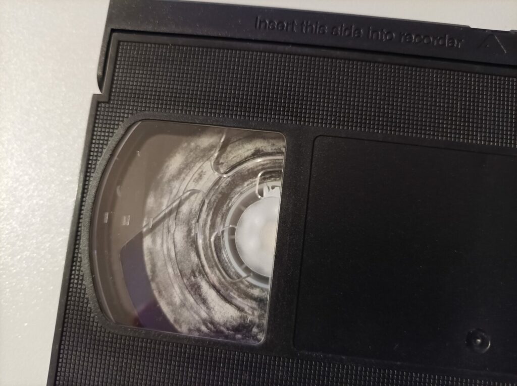 Cassette VHS présentant des traces de moisissures blanches sur la bande avant restauration